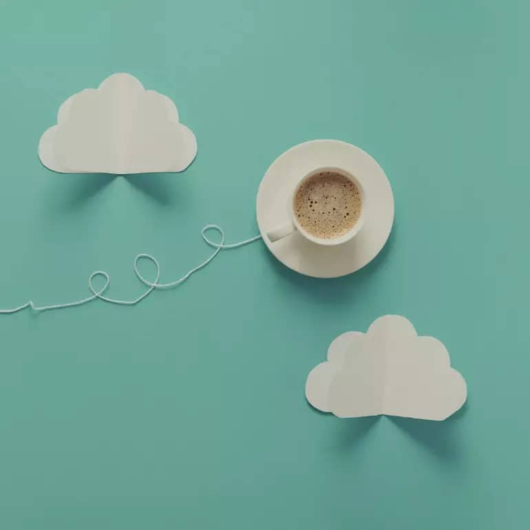 whimsical image of cup and saucer and paper clouds
